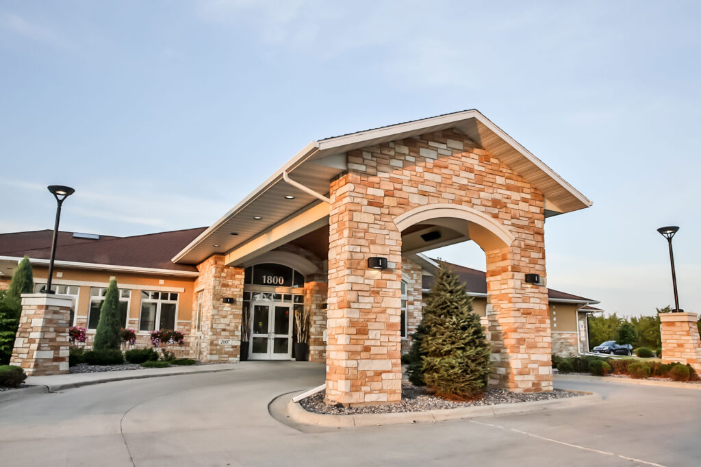 Exterior of a large clinic building with brick columns and a covered entryway for patient drop-off.